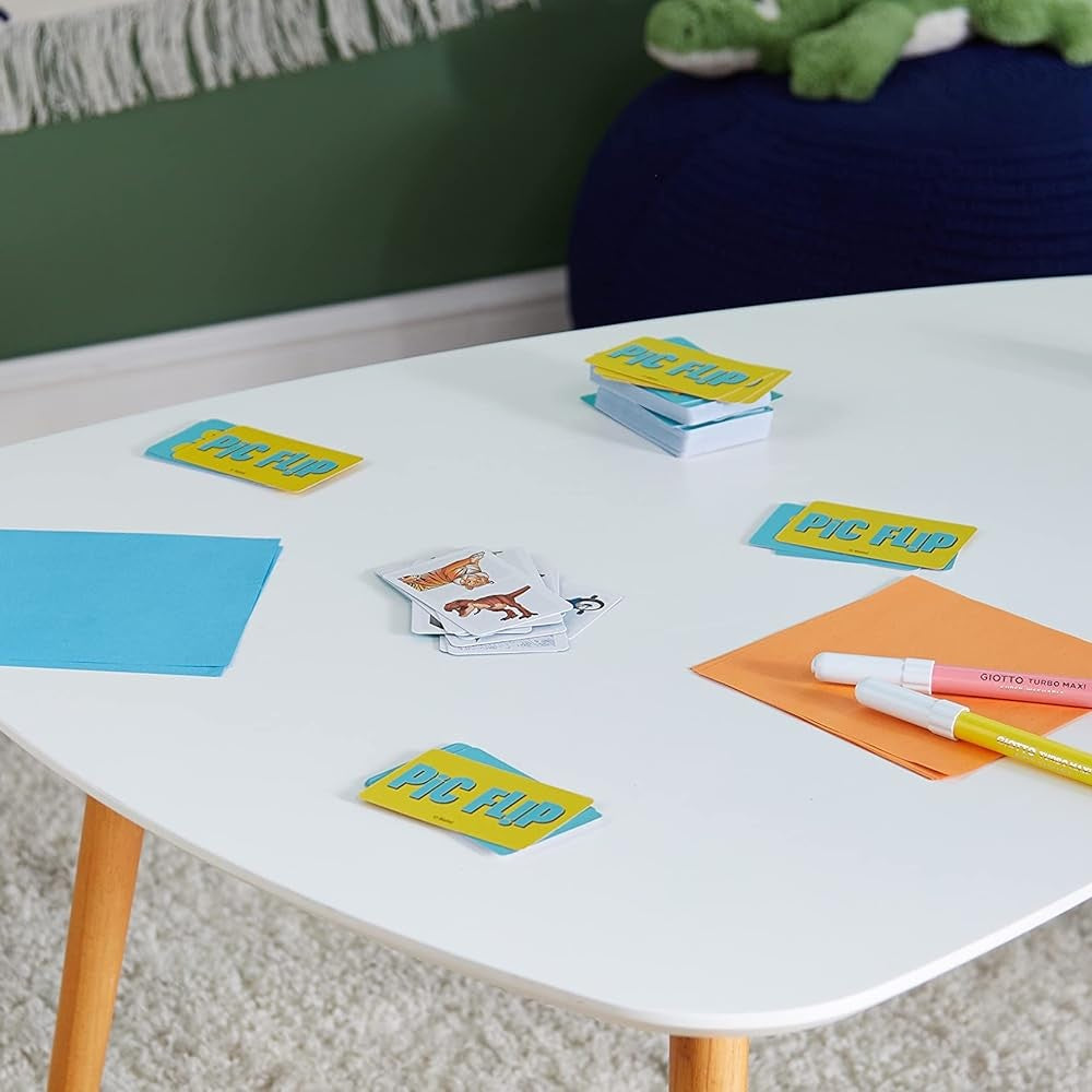 Colorful cards and markers on a white table with a green wall and toy in the background