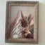 Wooden picture frame with a decorative plant inside on a plain background