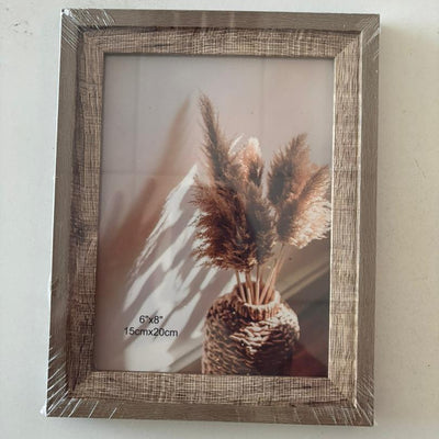 Wooden picture frame with a decorative plant inside on a plain background